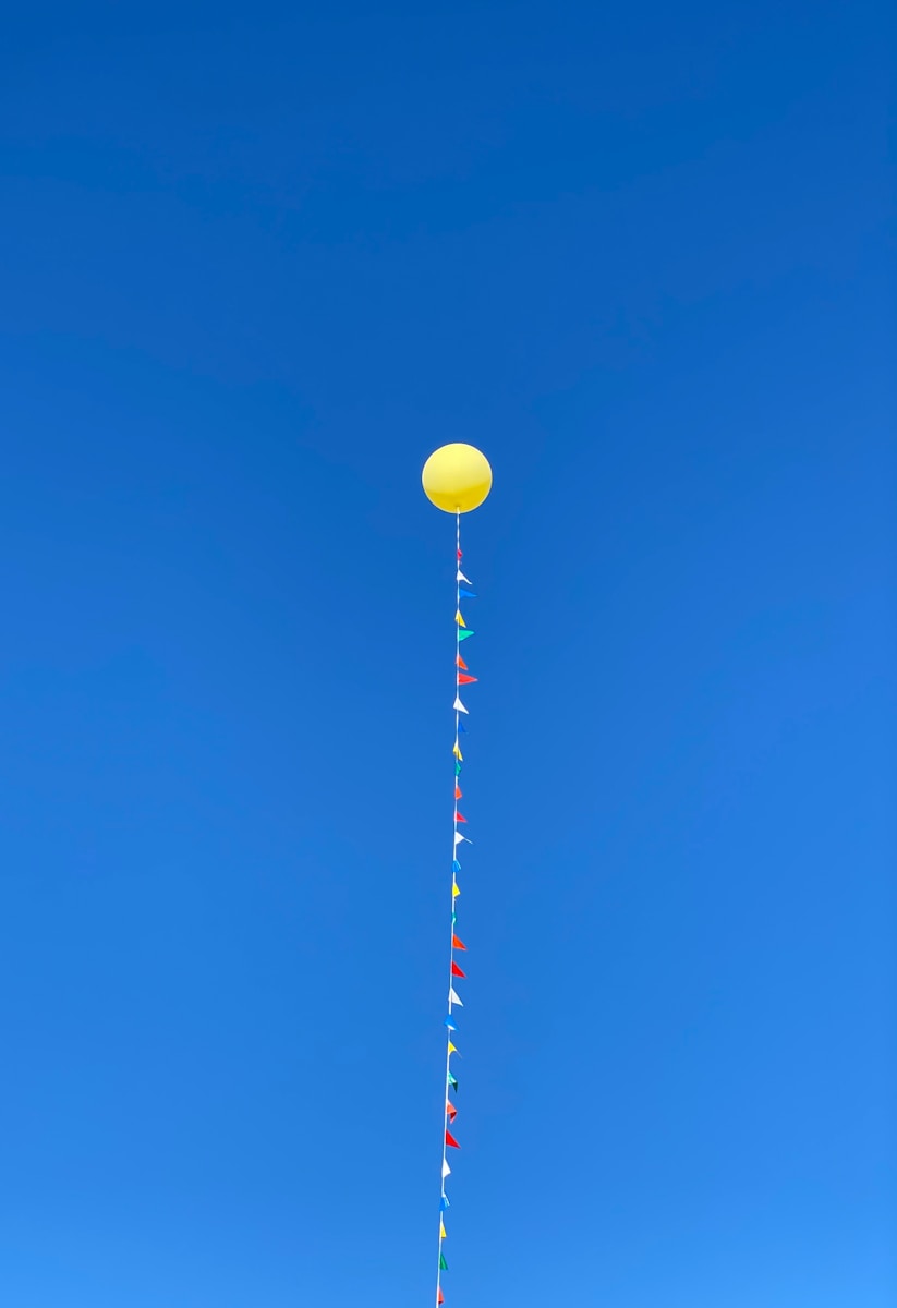yellow red and white balloons under blue sky during daytime