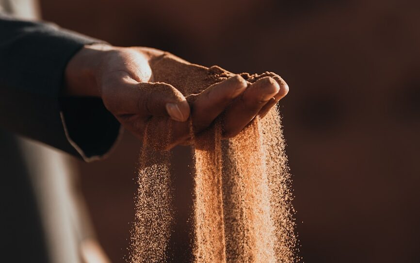 a person holding sand in their hands